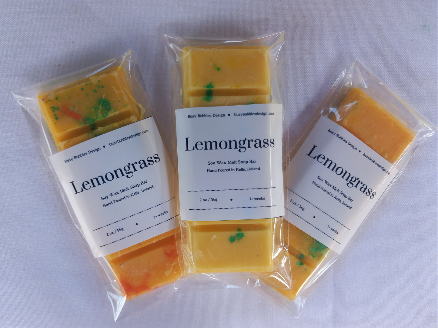 Three packages of lemongrass snap bars on a white background